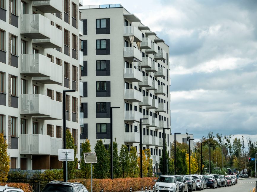 Suvremeni stambeni kompleks na ulici s parkiranim automobilima i jesenskim lišćem